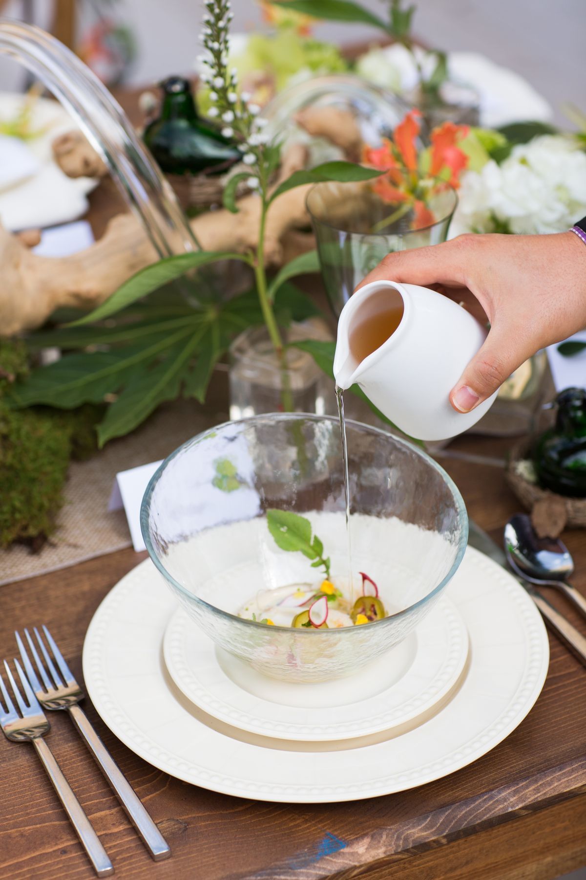 Pouring liquid into a white bowl placed on a table at Umstead Hotel and Spa