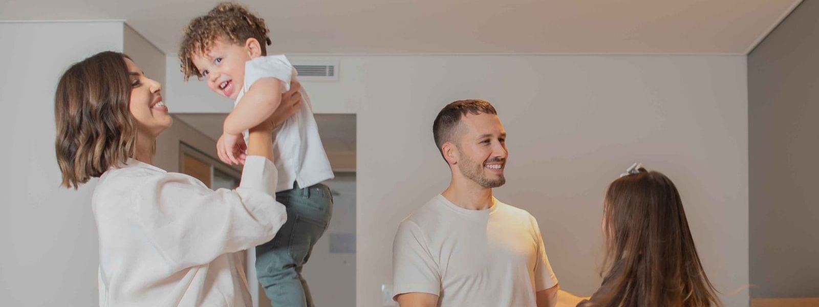Family of four playing together in a bright family room with two beds at Novotel Sydney Darling Harbour