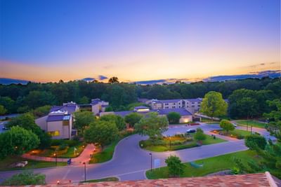 Aerial evening view of the Bolger Center, showing hotel buildings nestled in a lush, green forest