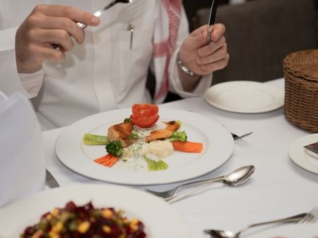 Guests dining with elegant meals and fine tableware at Al Duhaa Restaurant in Saja by Warwick Madinah.