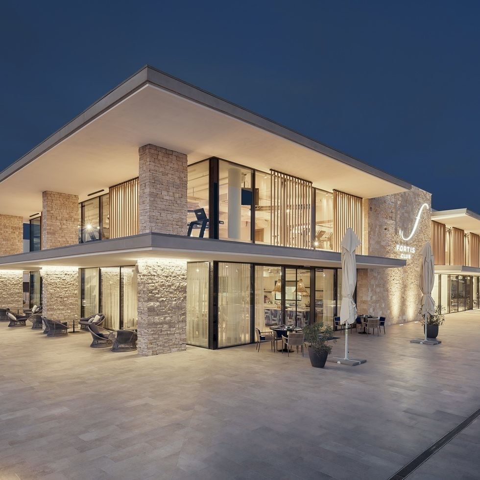 Esterno di un edificio moderno illuminato di notte con patio e mobili da esterno.