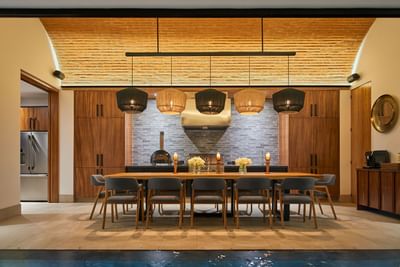 Casa Campanas dining room with long wooden table set for dinner under woven pendant lamps at Singular Signature Residences