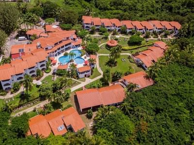 Aerial view of terracotta roof resort buildings with a large swimming pool and palm trees at Sugar Cane Club Hotel & Spa