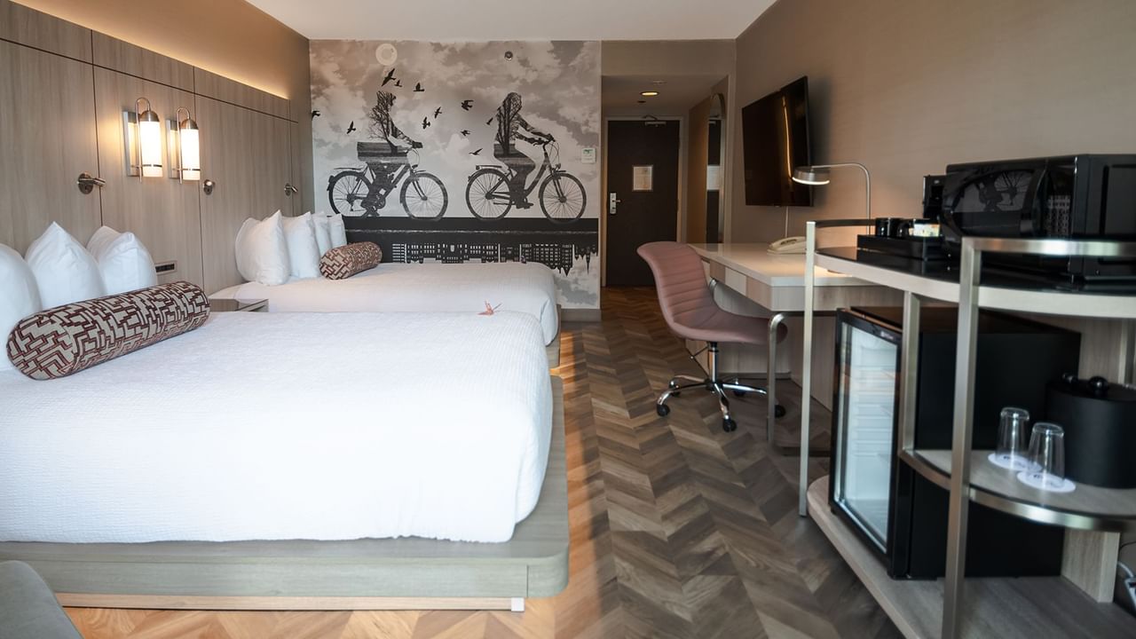 Hotel guestroom with two queen beds, mini fridge, microwave, TV, and work desk