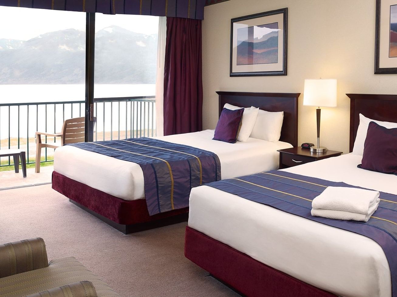 two beds in hotel room with balcony overlooking ocean