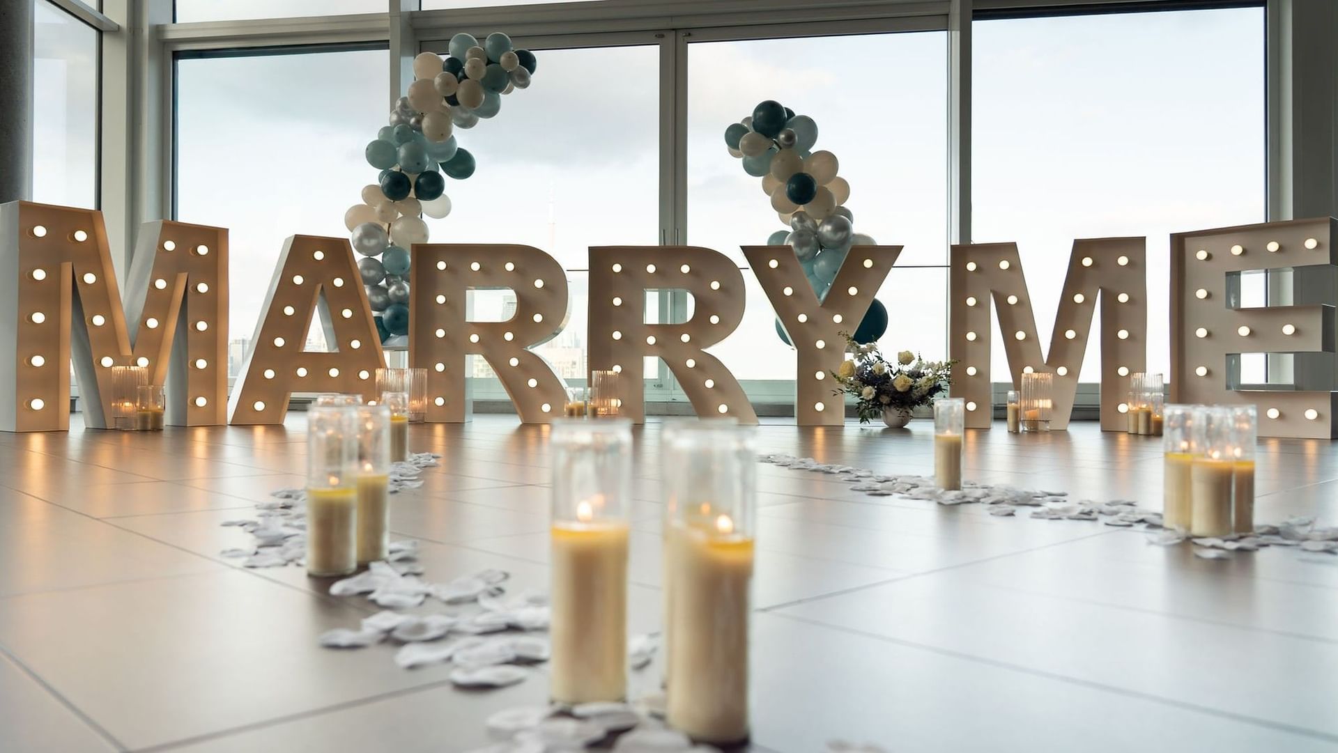 Illuminated MARRY ME marquee letters with balloon garland and candles in event space at Hotel X Toronto