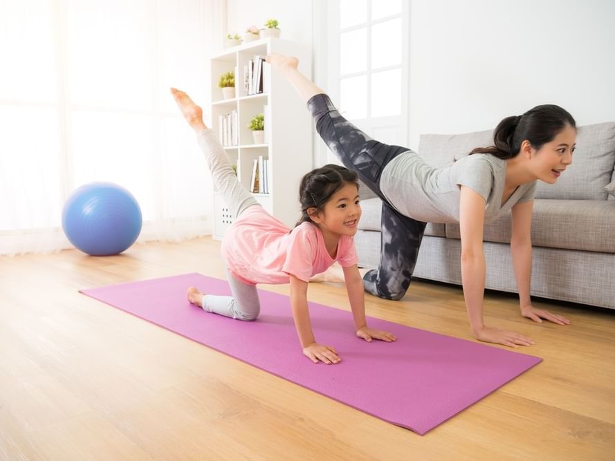 Woman & girl practicing yoga in a living room at Plymouth Hotel