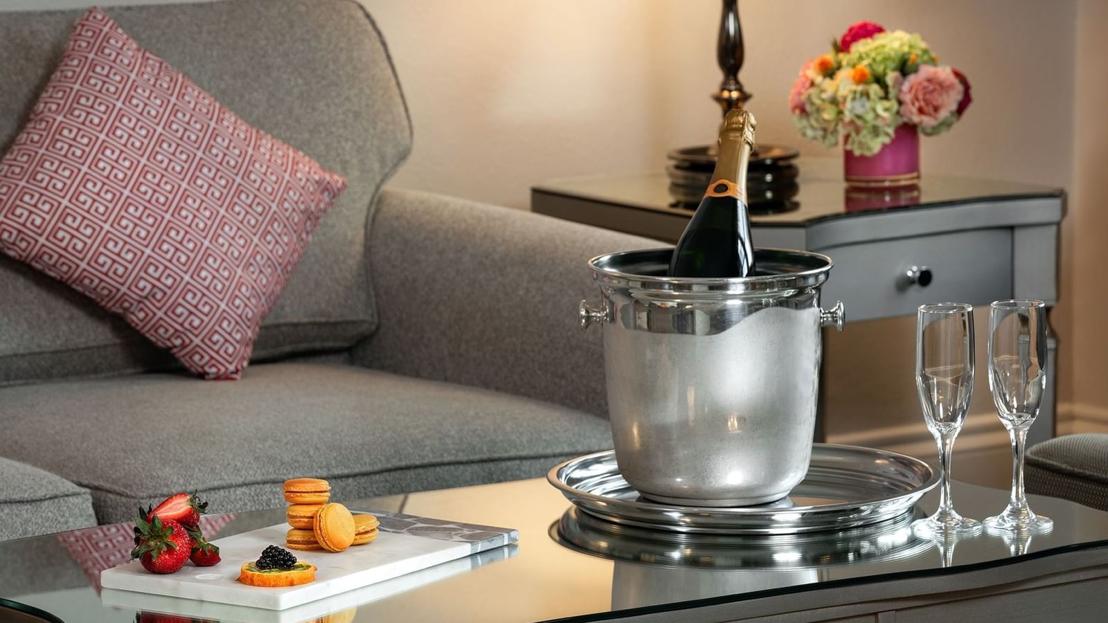 Champagne in a bucket by treats under a desk lamp at Warwick Melrose Dallas