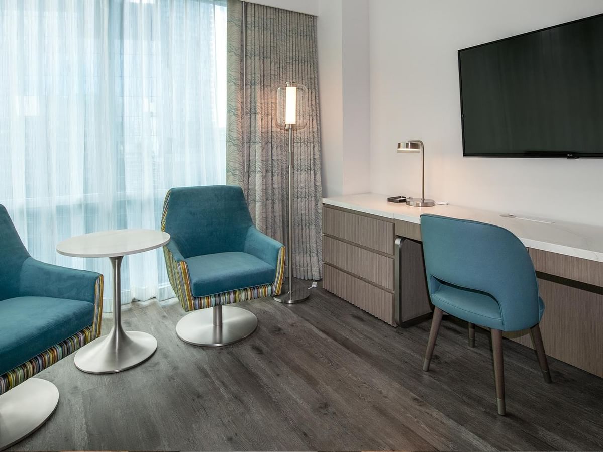 Interior of a hotel room with desk and chairs.
