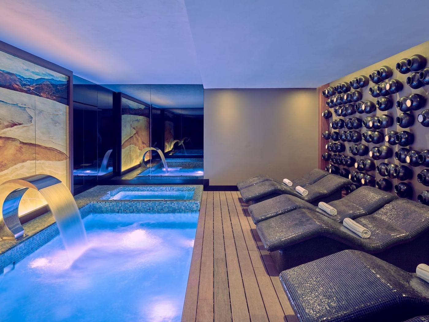 Indoor spa area with a serene pool featuring a waterfall, a jacuzzi & several dark mosaic lounge at Grand Fiesta Americana