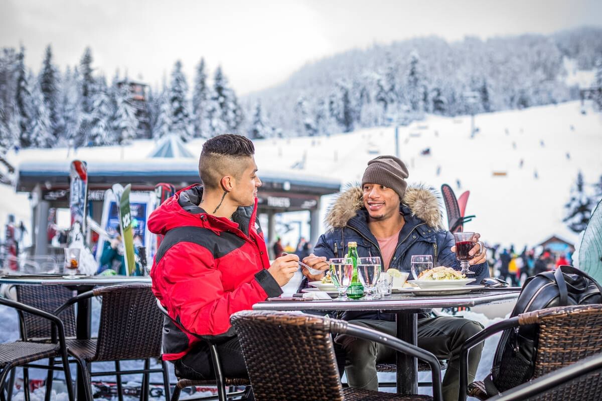 Men hanging out in a dining area on snow near Blackcomb Springs Suites