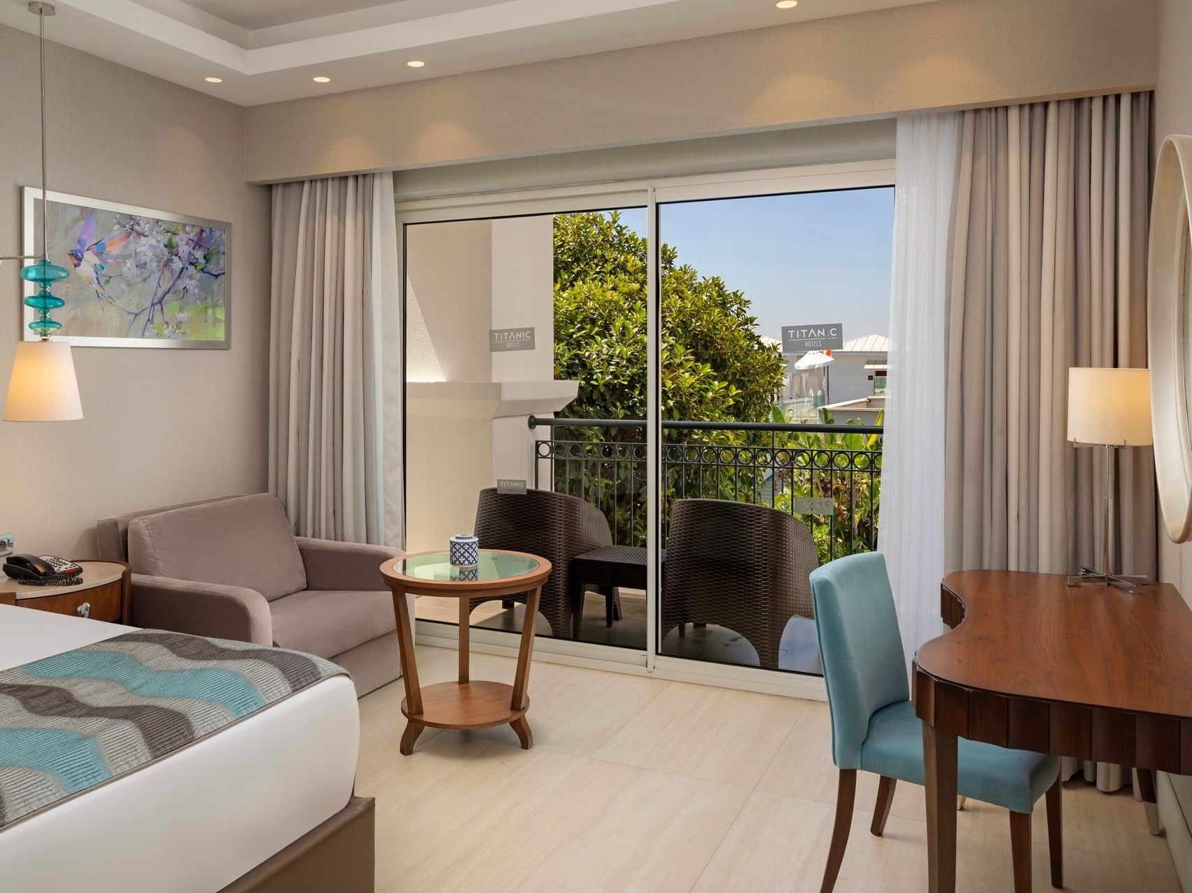 Modern hotel room with balcony view, seating area, desk, and contemporary furnishings at Titanic Deluxe Golf Belek