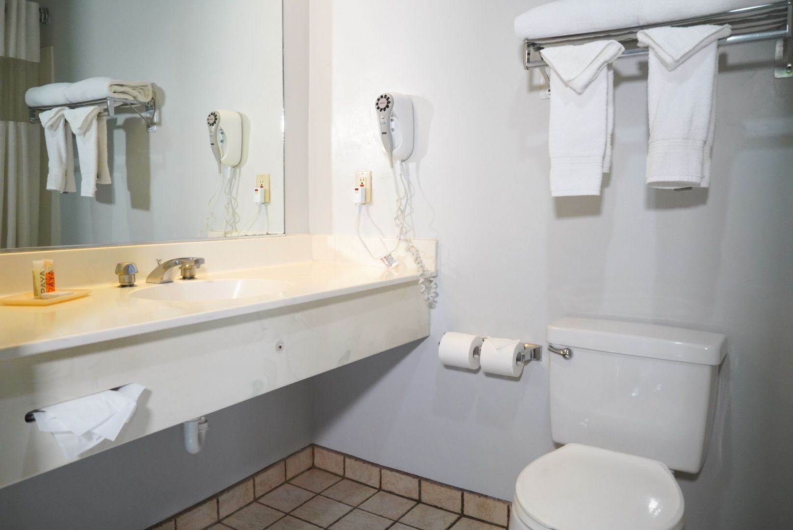 A standard hotel bathroom with a white sink, toilet, and mirror.