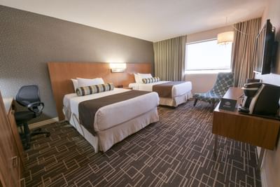 Two double beds and chair by window.