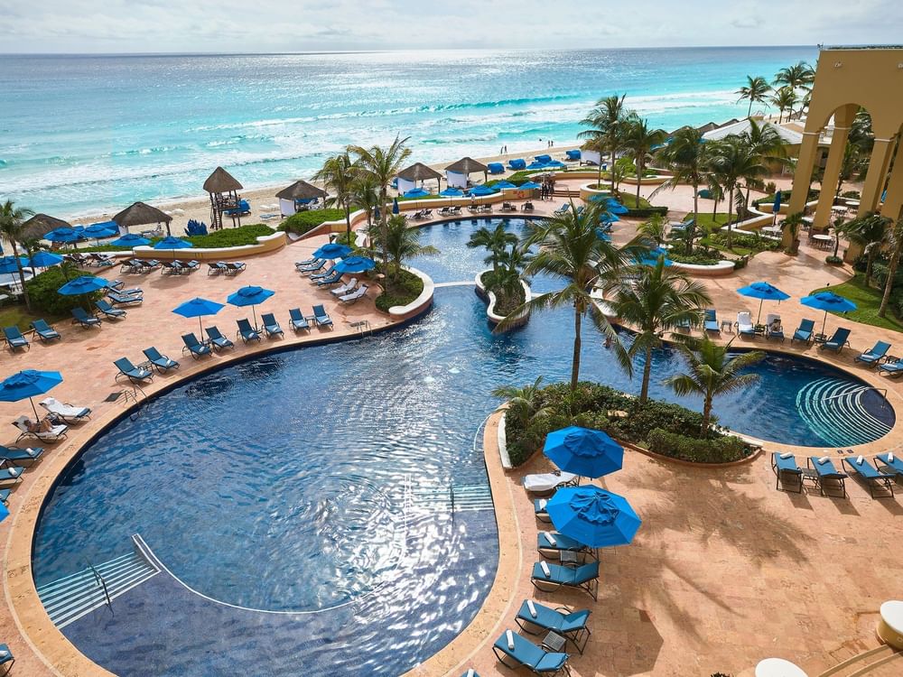 Aerial view of the North Pool enclosed by palm trees & sun loungers at Kempinski Hotel Cancún