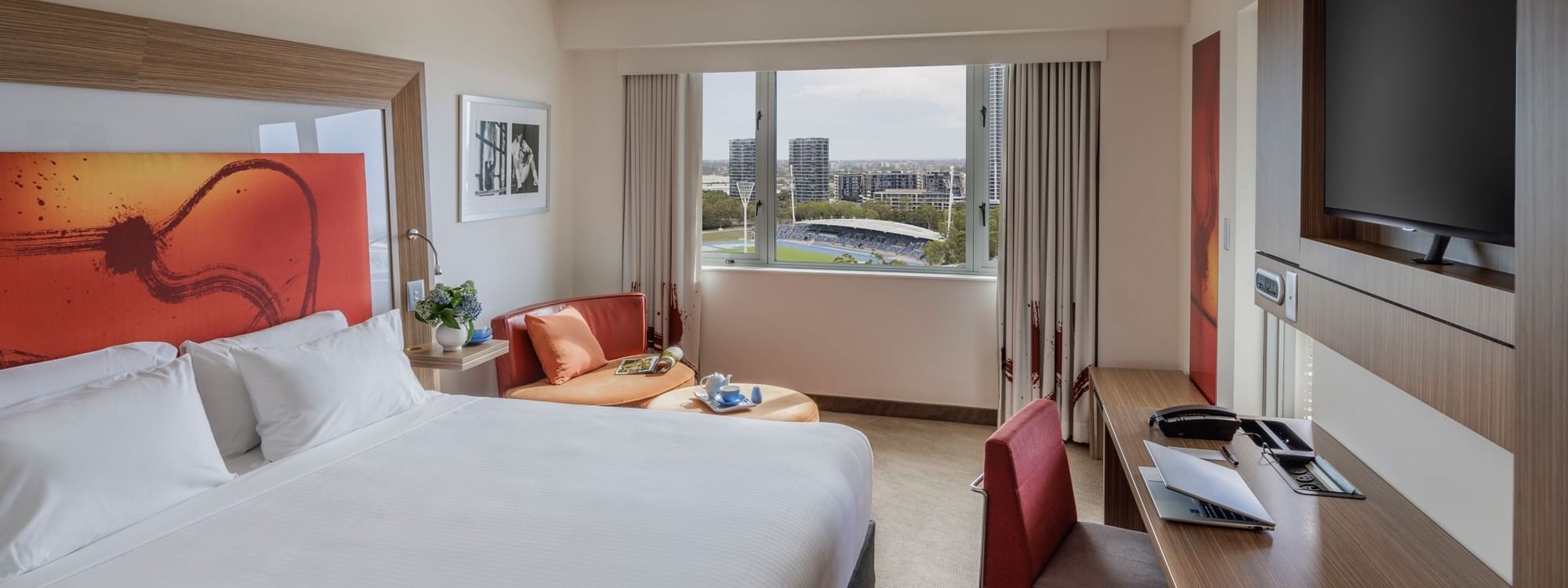 Wall-mounted TV, work desk & cozy seating area by the bed in Balcony Room at Novotel Sydney Olympic Park