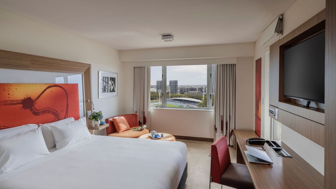 Wall-mounted TV, work desk & cozy seating area by the bed in Balcony Room at Novotel Sydney Olympic Park