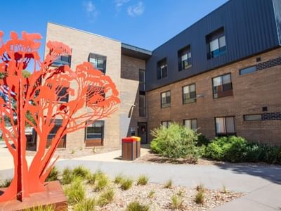 Exterior view of La Trobe University Hillside Apartments with modern architecture and red sculpture.