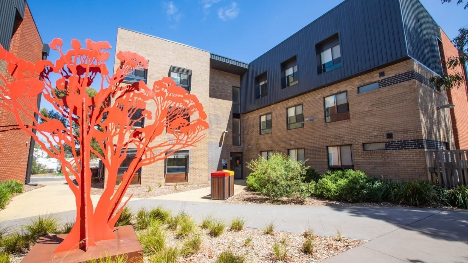 Exterior view of La Trobe University Hillside Apartments with modern architecture and red sculpture.