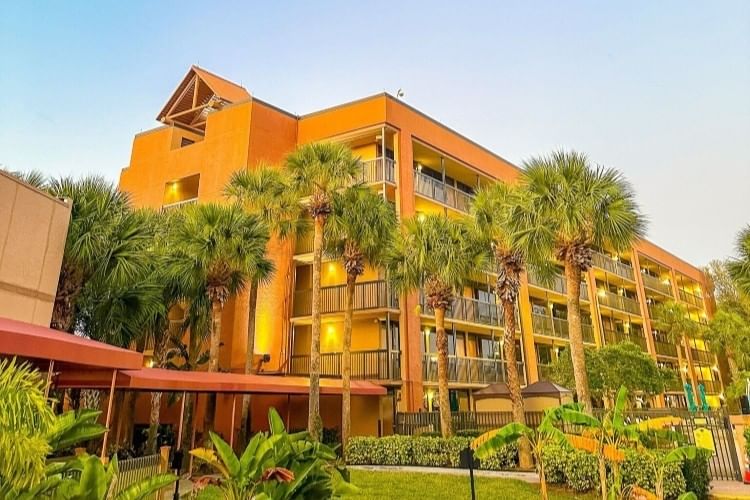 The outside of Rosen Inn Lake Buena Vista in Orlando at sunset, surrounded by palm trees. 