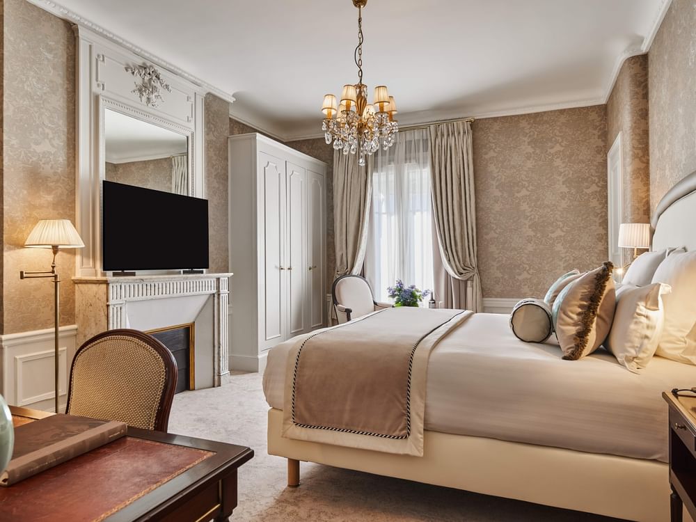 TV facing bed with couch and wood cupboard near window in Executive Room – Rue de la Paix View at Hotel Westminster Paris