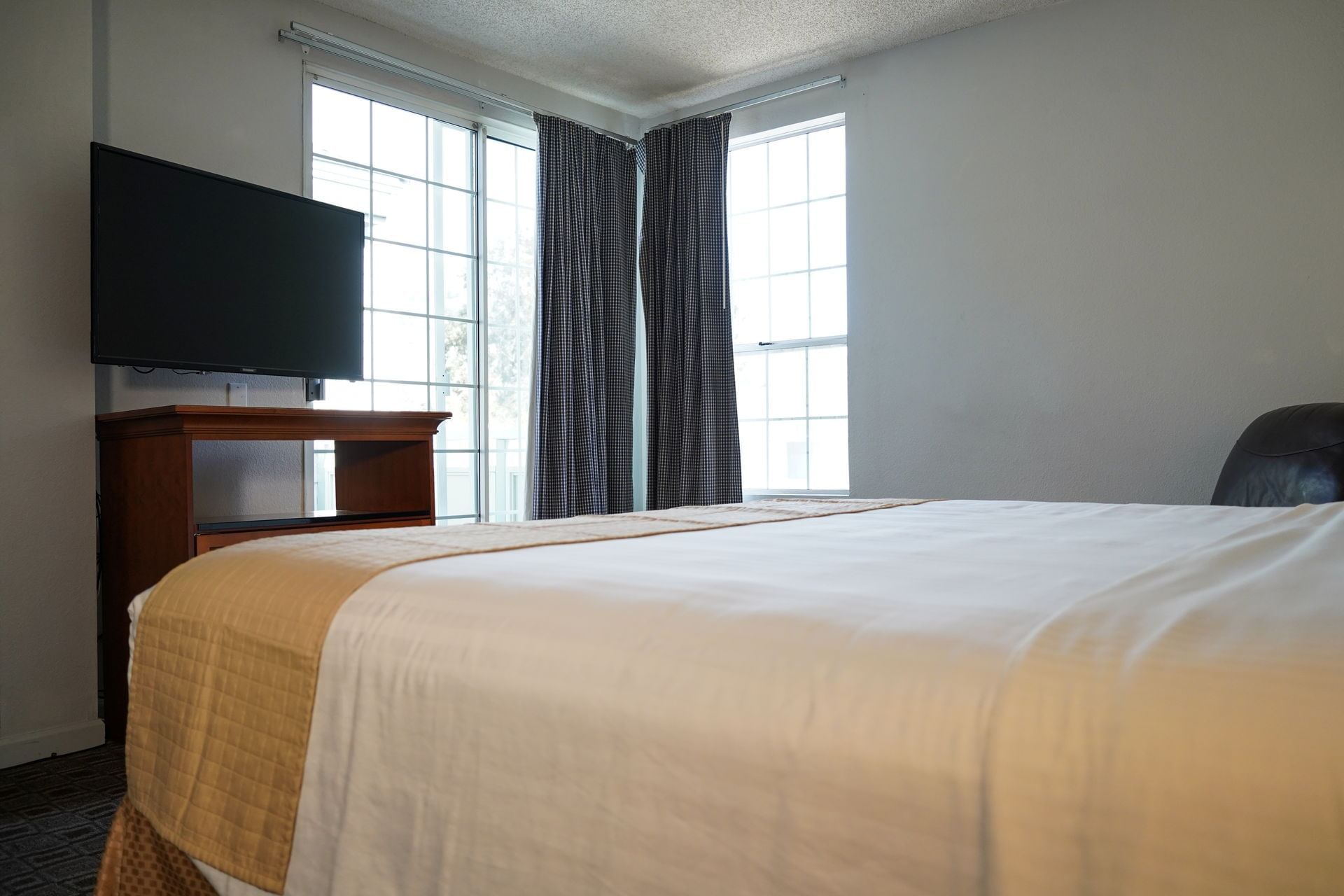 A hotel room with a bed, TV, and window.