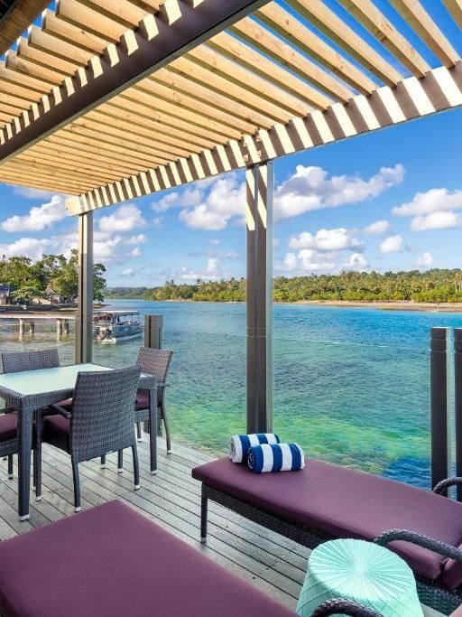 Outdoor overwater villa with wooden deck, dining area, and stunning sea views at Warwick Le Lagon - Vanuatu, Efate.