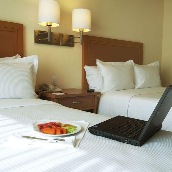 Laptop & fruit plate on bed in Superior Room at Fiesta Inn