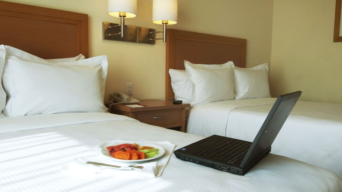 Laptop & fruit plate on bed in Superior Room at Fiesta Inn