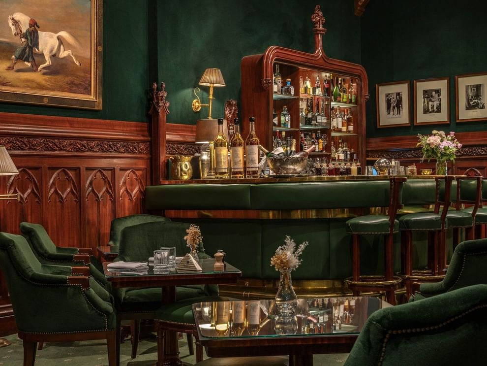 L'intérieur raffiné du Duke's Bar, avec ses chaises vertes, ses tables en bois et sa grande cheminée, à l'Hôtel Westminster - Paris.