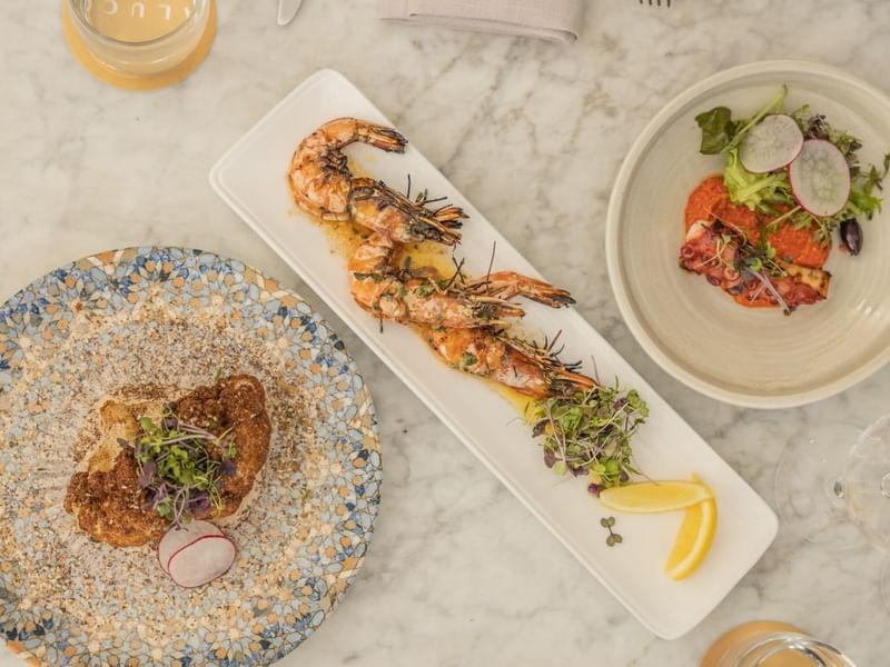 Overhead shot of table with grilled shrimp, salad & toast in Aluco restaurant and Bar at Pullman Port Douglasa