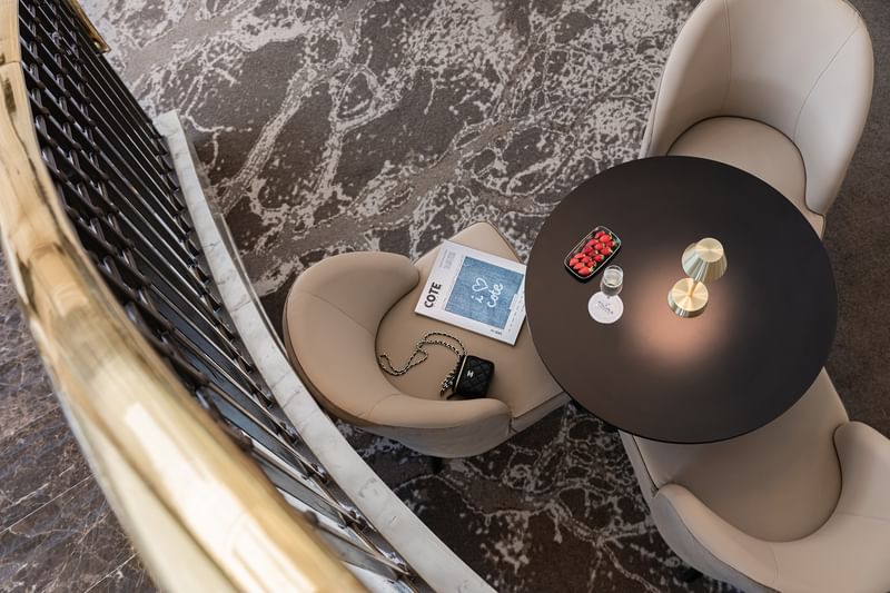 Lounge area featuring beige chairs by a black table under a golden lamp near a balcony at Warwick Geneva