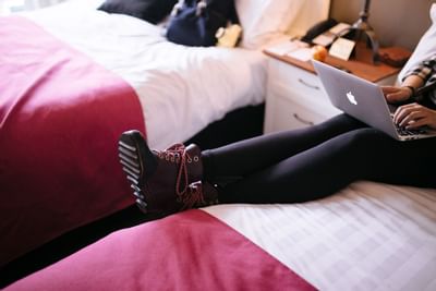 Woman on the bed while using a laptop at Summit Lodge