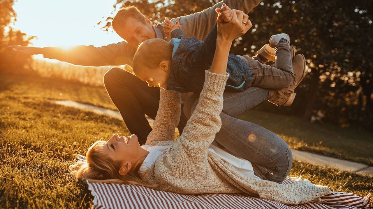 mom holding child on her knees with arms spread out