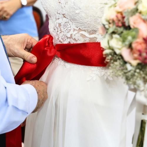 bride getting red ribbon tied around her waist which is a traditional Turkish wedding tradition