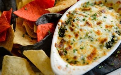 Warm spinach & artichoke dip in an oval dish with tri-color tortilla chips at Clemson University Conference Center & Inn