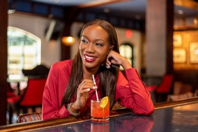 A lady drinking a cocktail in Mingles Bar & Lounge at Courtleigh Hotel and Suites