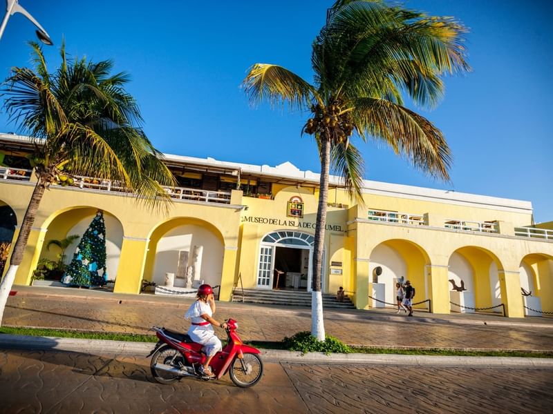 Sunny day at Cozumel Museum with yellow arches and palm trees, located near The Explorean Resorts