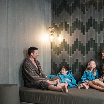 A family in bathrobes lounging in a spa at Falkensteiner Hotels