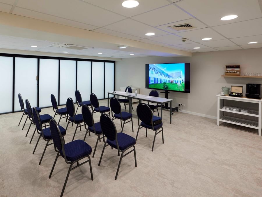 Salle de réunion avec chaises bleues et écran à l'Hôtel La Marébaudière.