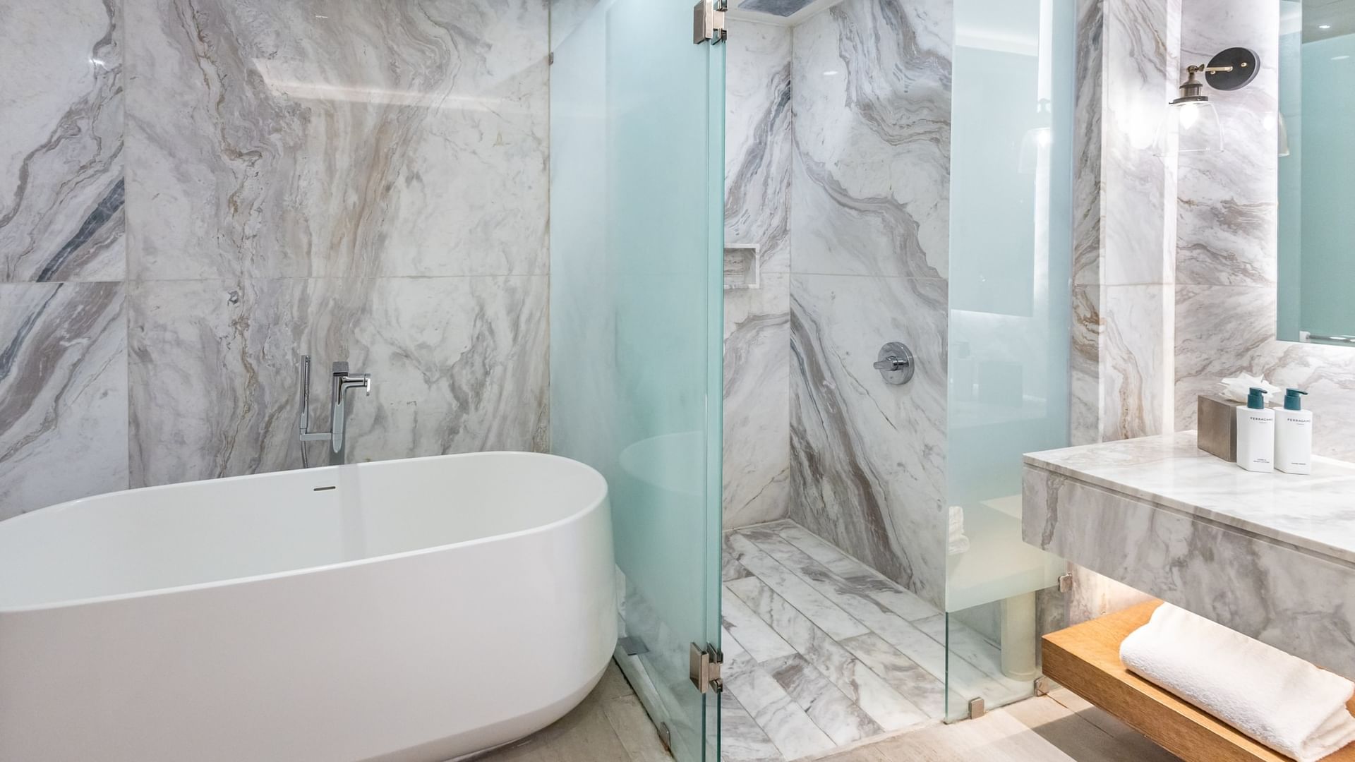 Modern bathroom with freestanding tub, glass-enclosed shower, and gray marble walls at Quinta Real Monterrey.