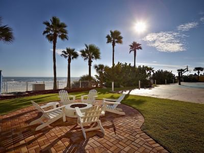 adirondack chairs surrounding fireplace with ocean view