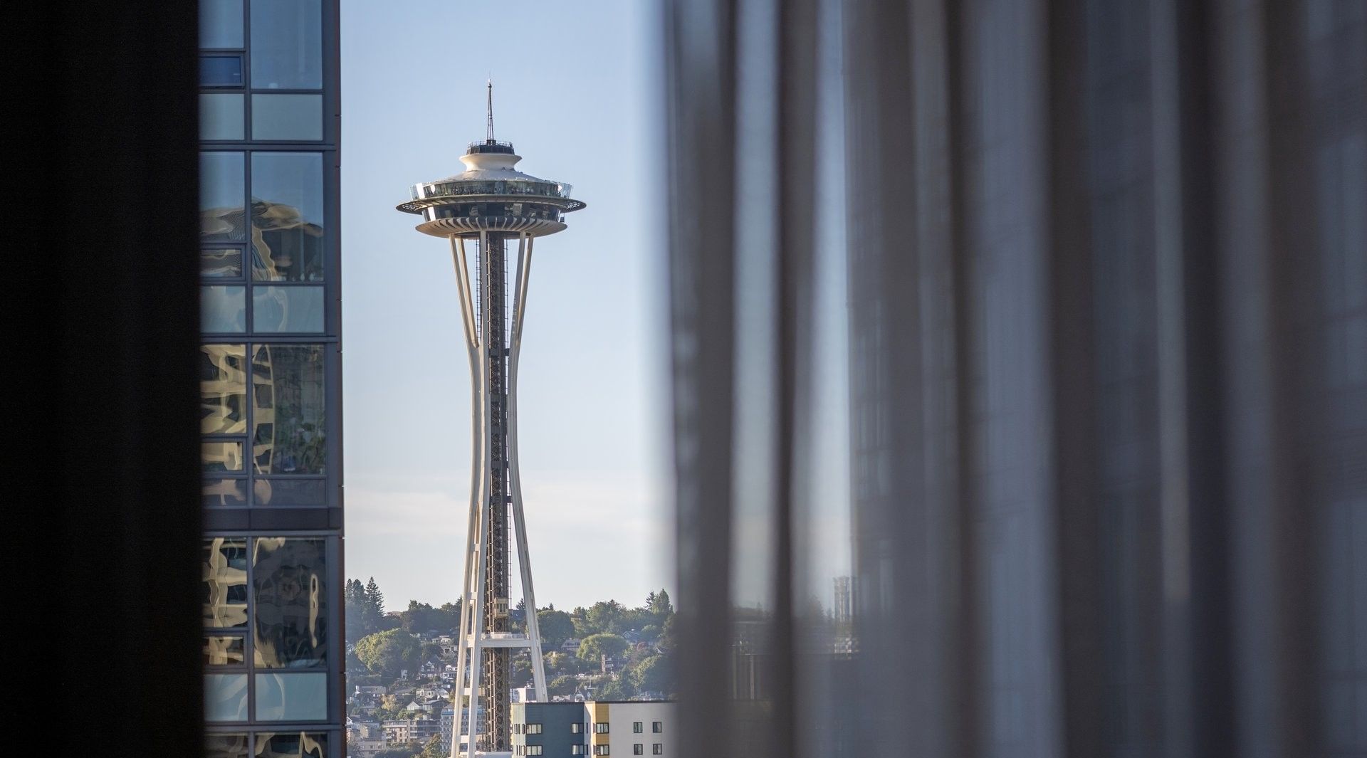 View through a sheer curtain frame of the Space Needle and city buildings near Warwick Seattle