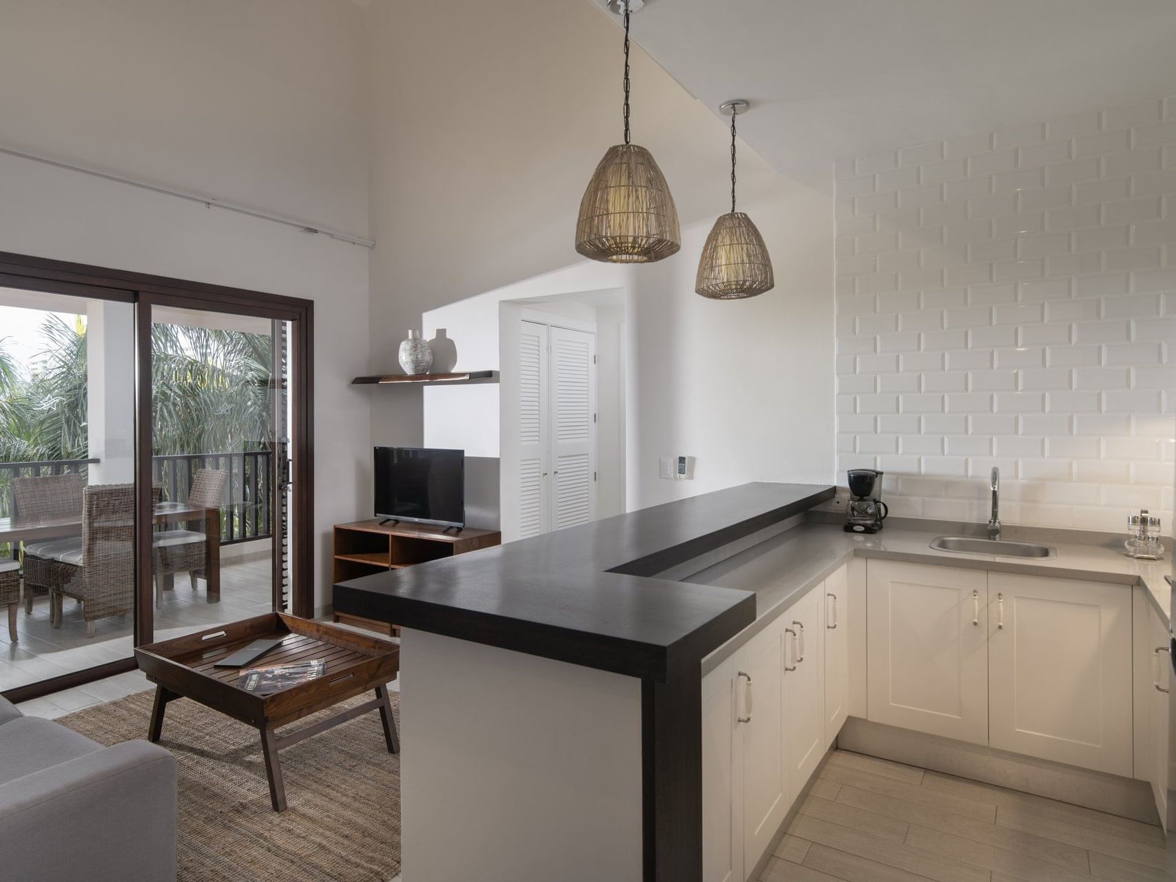 Studio Junior Suite kitchen with a dark countertop, breakfast bar, white tiled backsplash, and balcony view at Club Hemingway