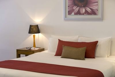Bed with cushions & night lamp at Nesuto Hotels