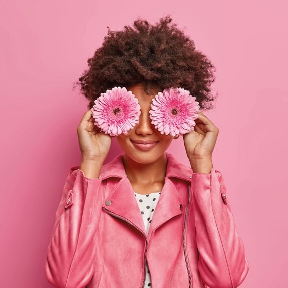 Woman holding two flowers on her eyes
