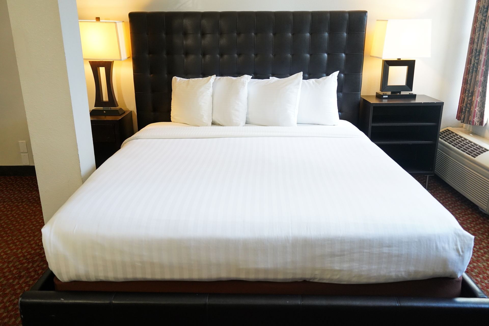 A neatly made hotel bed with a tufted headboard, flanked by nightstands with lamps.