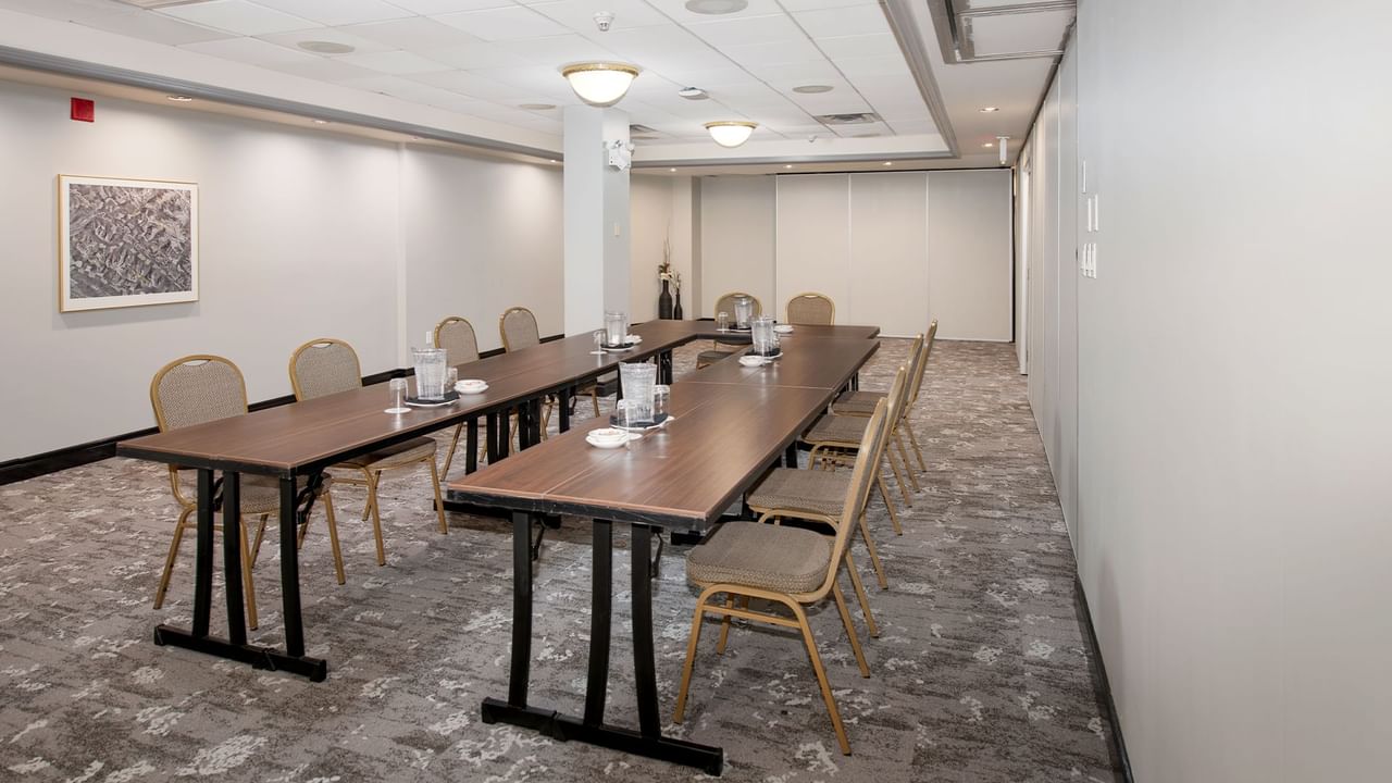 A meeting room with long tables, chairs, and a framed artwork on the wall.