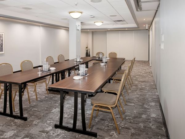 A conference room with long tables, chairs, and a framed artwork on the wall.
