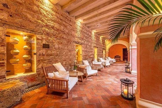 Colonial brick-walled hallway of the Charleston Santa Teresa Hotel combined with modern wooden furniture.